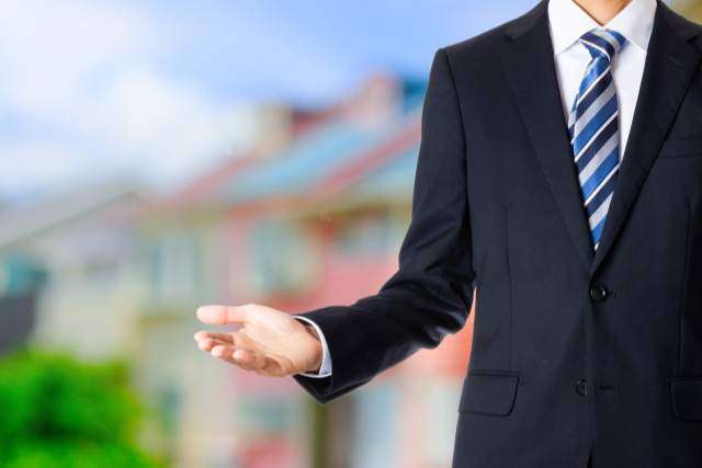 家を背景にしたスーツの男性