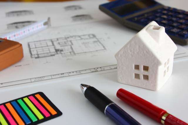 設計図と電卓と家の模型とペン