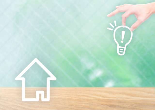 家と電球を持った手