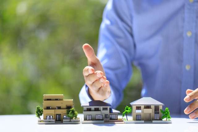 3つの家の模型と男性の手