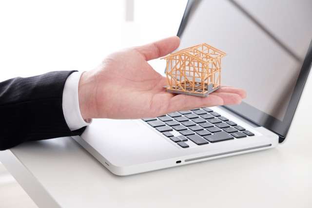 家の骨組みの模型を持った手