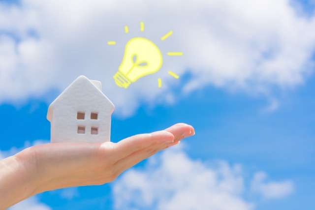 家の粘土細工を持った手と電球